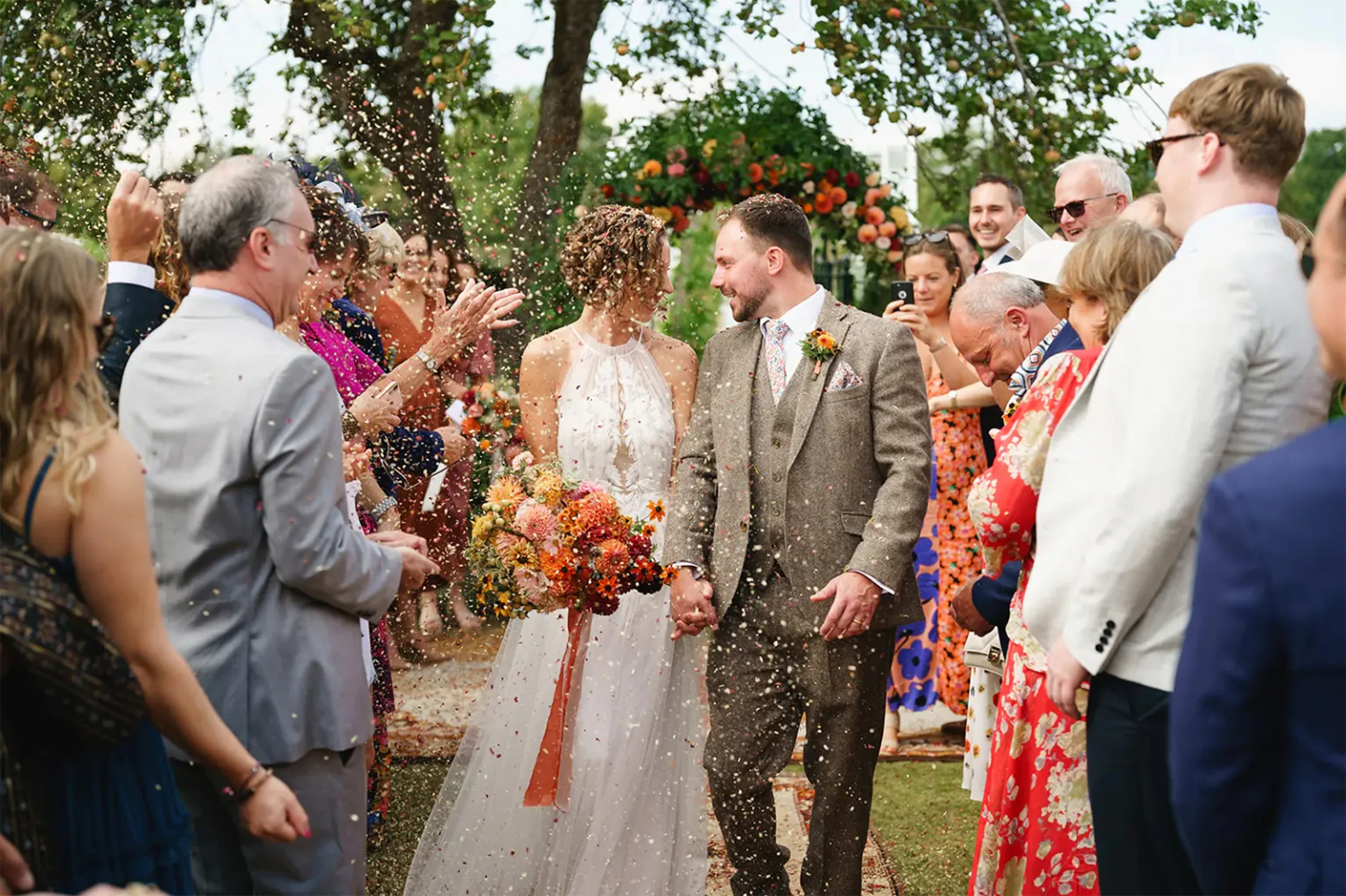 Newlyweds surrounded by wedding guests taking pictures during a confetti exit