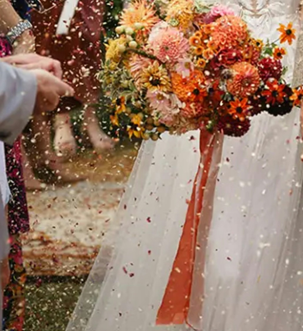 A colorful wedding bouquet and ribbons against a white dress