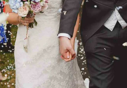 Newlyweds holding hands amid falling confetti, with a wedding bouquet