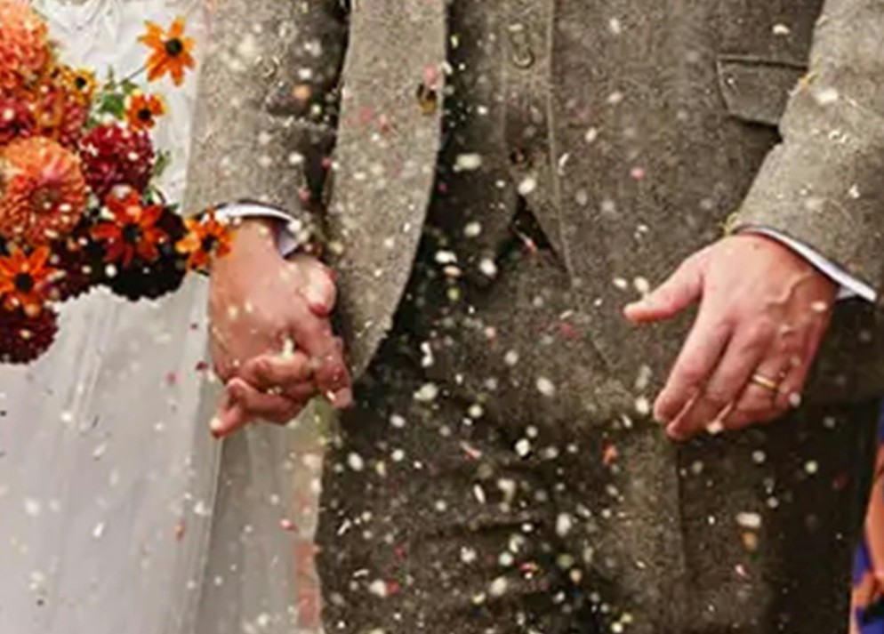 A couple holding hands beside their bouquet during a confetti celebration